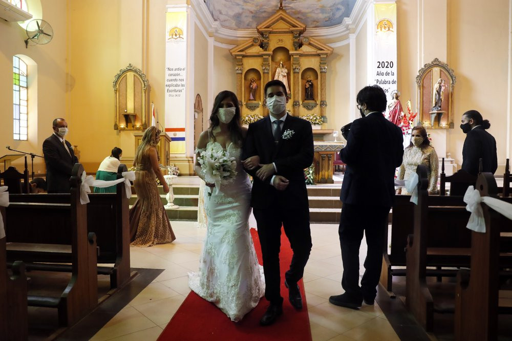 Bride Jazmin Sanabria and her groom Joel Adorno, wearing protective face masks amid the new coronavirus pandemic, walk down the aisle in the first wedding ceremony since 101 days of quarantin