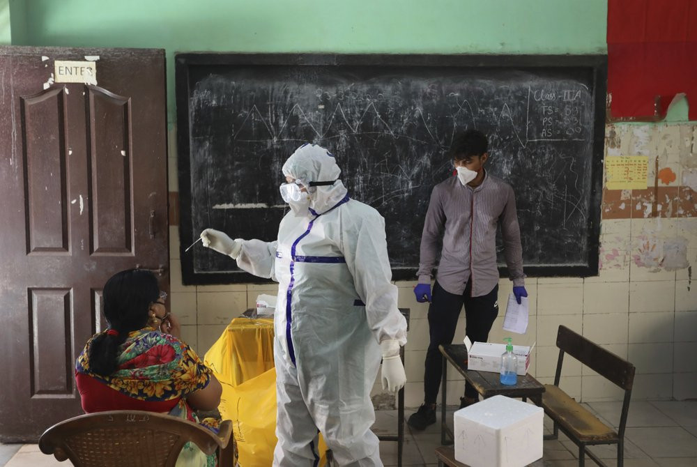 In this Wednesday, June 24, 2020, photo, a health worker takes a swab sample of a woman for a COVID-19 test in New Delhi, India.