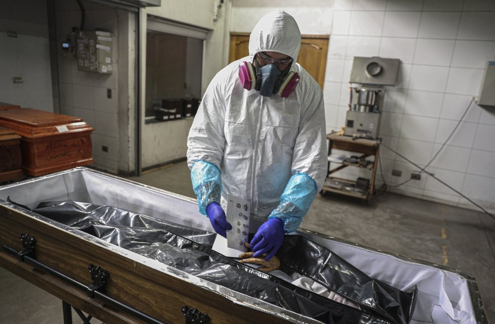 An employee takes the fingerprints of a woman who died from the new coronavirus before her remains are cremated at La Recoleta crematorium in Santiago, Chile, Saturday, June 27, 2020.