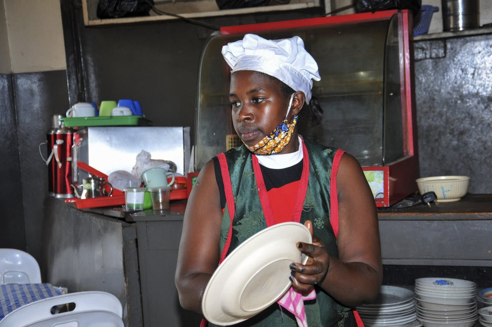 In this photo taken Saturday, June 20, 2020, Rebecca Nakamanya works at a restaurant near a bus terminal in capital Kampala, Uganda.