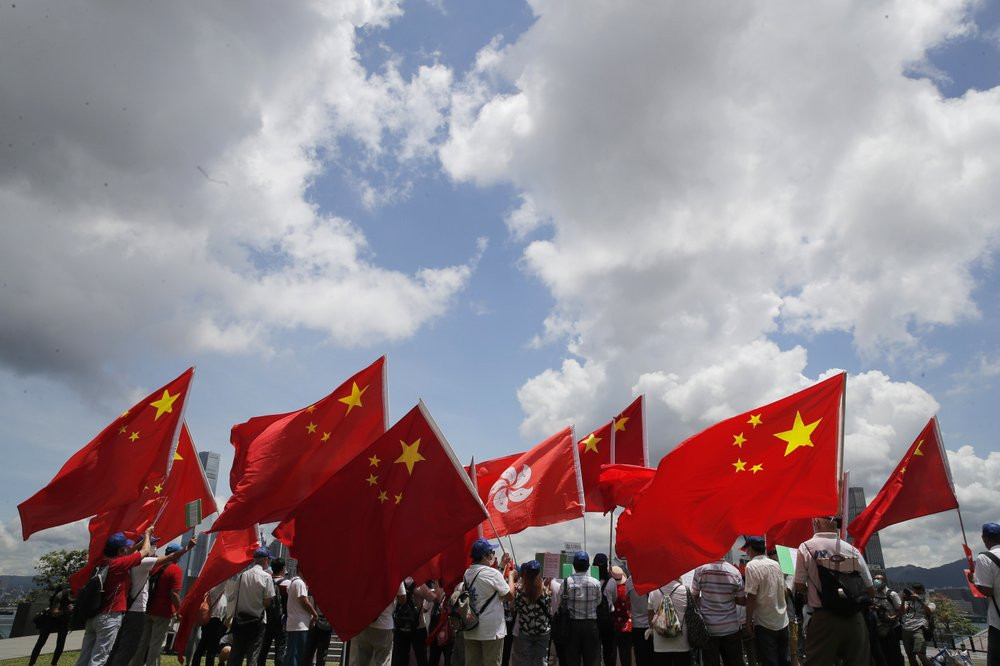 Pro-China supporters hold Chinese and Hong Kong national flags during a rally to celebrate the approval of a national security law for Hong Kong, in Hong Kong, Tuesday, June 30, 2020.