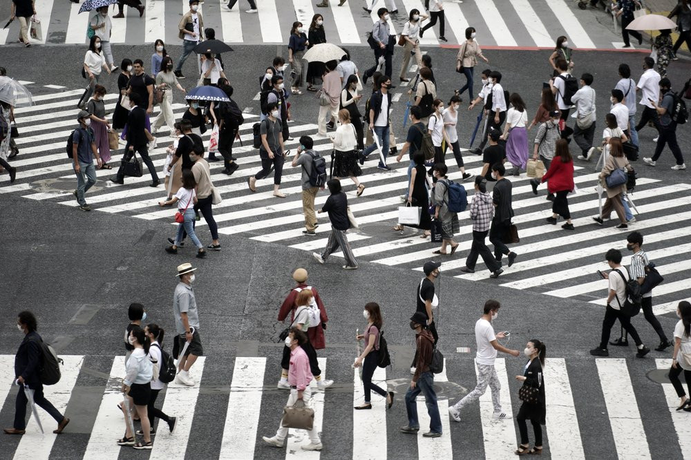 People wearing a protective face mask to help curb the spread of the coronavirus walk at Shibuya pedestrian crossing Thursday, July 9, 2020, in Tokyo.