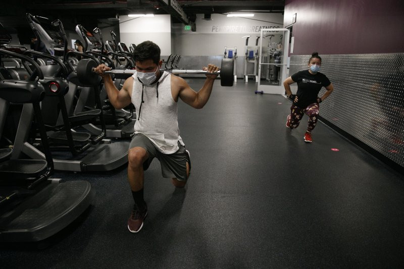 In this June 26, 2020 file photo, people wear masks while exercising at a gym in Los Angeles. On Thursday, July 9, 2020, the WHO is acknowledging the possibility that COVID-19 might be spread