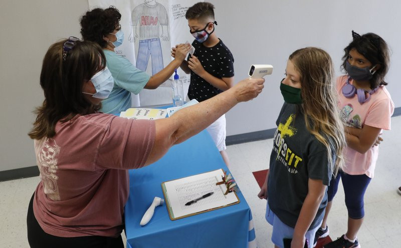 In this Tuesday, July 14, 2020 file photo, Amid concerns of the spread of COVID-19, teachers check students before a summer STEM camp at Wylie High School in Wylie, Texas.