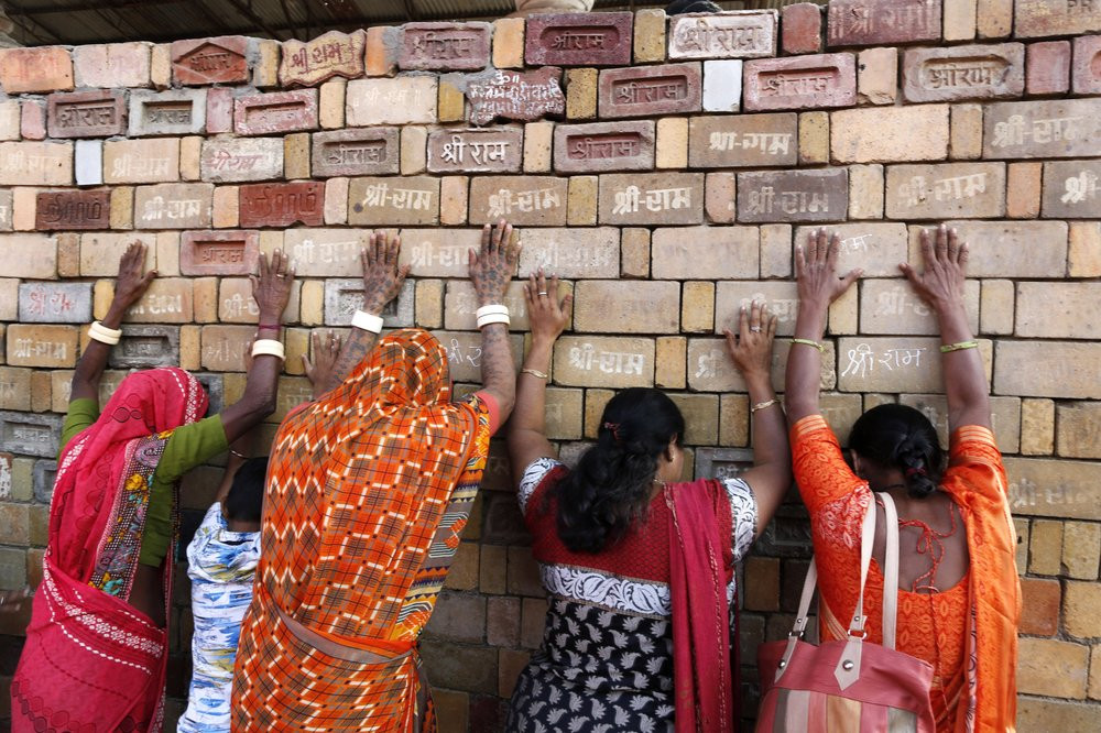 In this Nov. 11, 2019 file photo, Hindu women devotees pray to the bricks reading "Shree Ram" ( Lord Ram), which are expected to be used in constructing Ram temple, in Ayodhya, India.