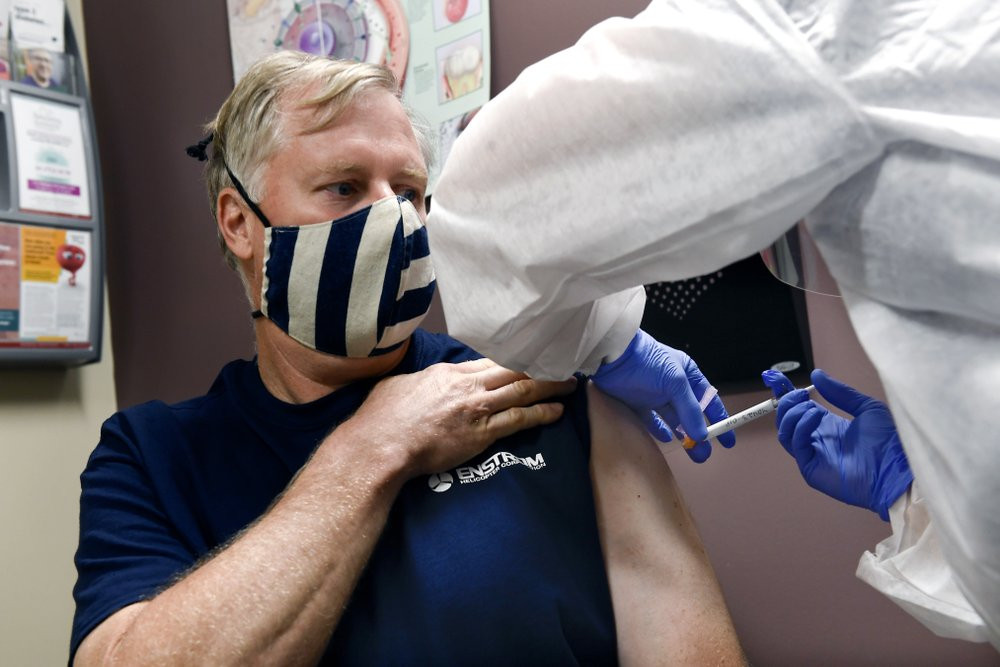 Nurse Carolyn Grausgruber gives volunteer Ithaca firefighter Wade Bardo, of Erin, N.Y., an injection as the world's biggest study of a possible COVID-19 vaccine, developed by the National Ins