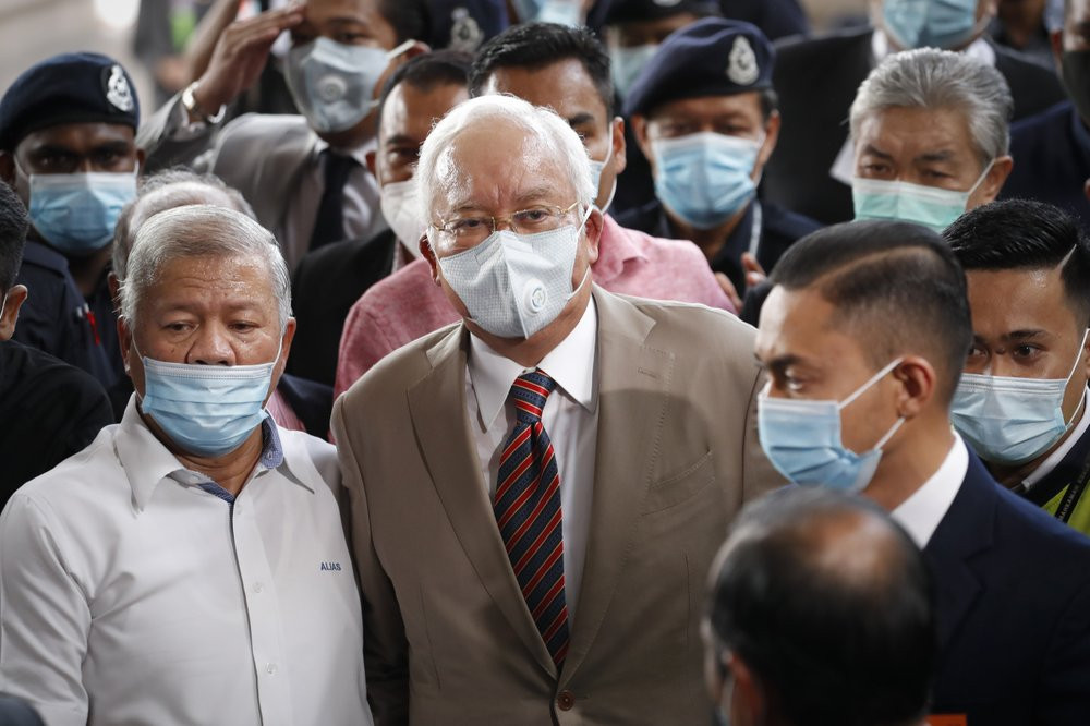 Former Malaysian Prime Minister Najib Razak, center, wearing a face mask with his supporters arrives at courthouse in Kuala Lumpur, Malaysia, Tuesday, July 28, 2020.