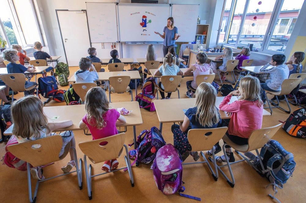 Teacher Francie Keller welcomes the pupils of class 3c in her classroom in the Lankow primary school to the first school day after the summer holidays in Schwerin, Germany, Monday, Aug. 3, 20