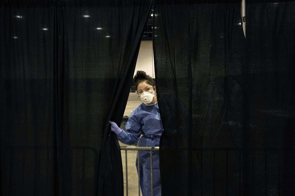 Diana Vega, a registered respiratory therapist, peeks through a curtain during setup at a temporary coronavirus testing site Monday, Aug. 3, 2020, in Las Vegas.