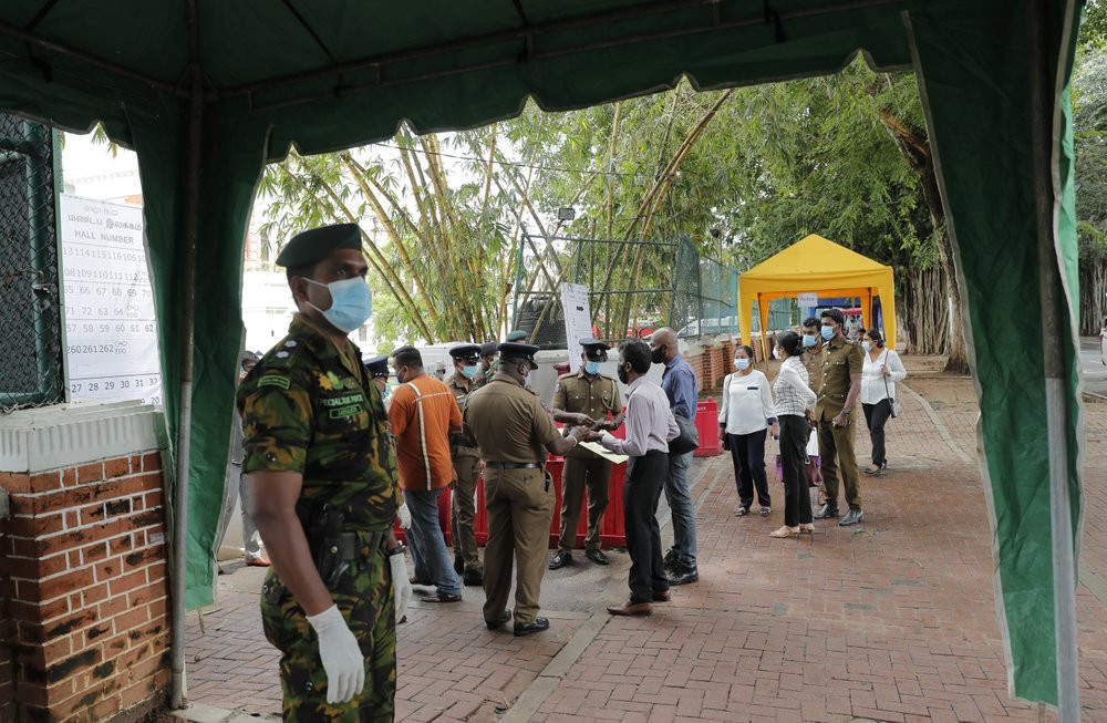 A Sri Lankan government soldier stands guard at the entrance to a ballot counting center as workers show their identity to police officers, a day after voting for general elections in Colombo