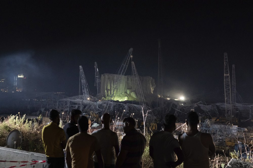 People look at the scene of Tuesday's explosion that hit the seaport of Beirut, Lebanon, Friday, Aug. 7, 2020.