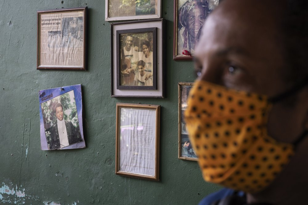 Marcio Antonio do Nascimento stands next to a framed childhood image of his 25-year-old son Hugo do Nascimento who died from the new coronavirus, in Rio de Janeiro, Brazil, Saturday, Aug. 1, 