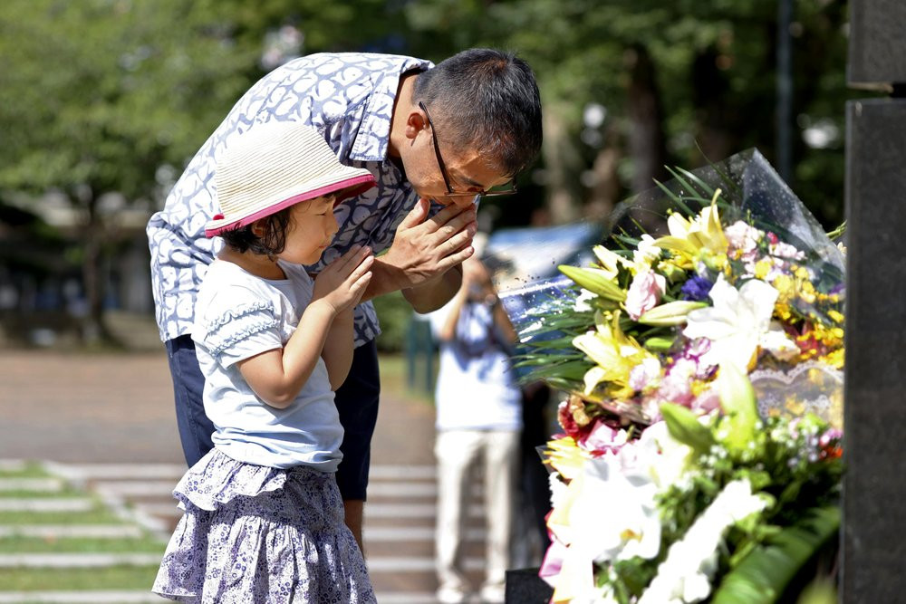 A man and his daughter pray for the victims of U.S. atomic bombing at the Atomic Bomb Hypocenter Park in Nagasaki, southern Japan, Sunday, Aug. 9, 2020.
