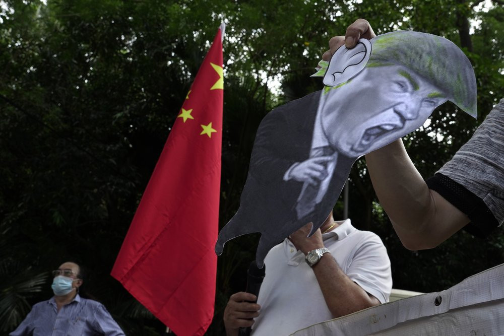 In this Aug. 8, 2020, file photo, pro-China supporters display a picture of U.S. President Donald Trump during a protest against the U.S. sanctions outside the U.S. Consulate in Hong Kong.