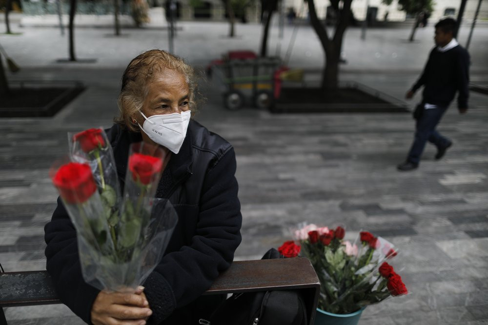 Wearing a mask to curb the spread of the new coronavirus, Martha Gonzalez Reyes, 76, sells roses outside Metro Hidalgo in central Mexico City, Monday, Aug. 10, 2020.