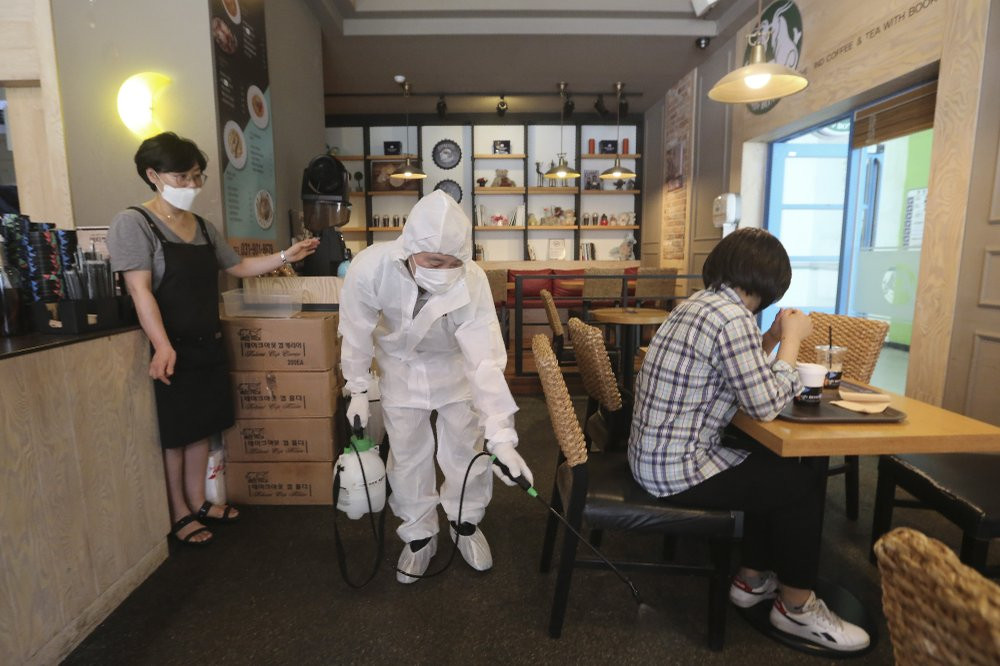 A worker disinfects as a precaution against the coronavirus at a cafe in Goyang, South Korea, Tuesday, Aug. 25, 2020.