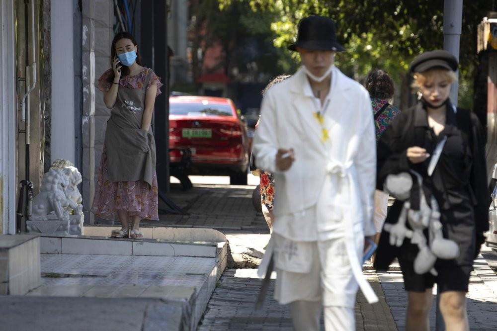 A resident wears a mask to curb the spread of the coronavirus as she speaks on her phone in Beijing on Monday, Aug. 24, 2020.