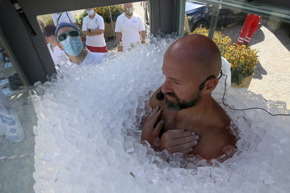 Austrian ice swimmer Josef Koeberl is standing in a glass cabin filled with ice try to break the world record for a human to stay side an ice box in Melk, Saturday, Sept. 5, 2020.