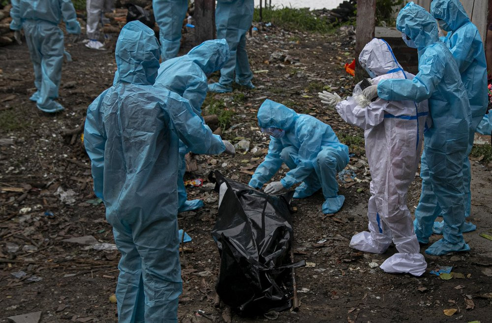 A woman, wearing white personnel protective equipment, reacts as she takes a glimpse of her husband's body, a victim of COVID-19, in Gauhati, India, Thursday, Sept. 10, 2020.