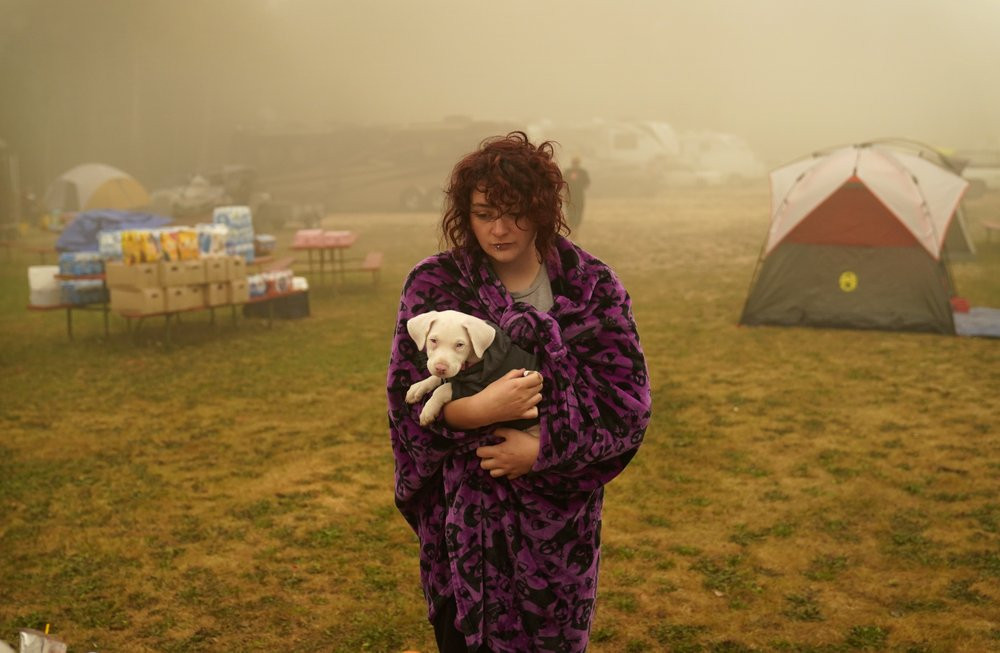 Shayanne Summers holds her dog Toph while wrapped in a blanket after several days of staying in a tent at an evacuation center at the Milwaukie-Portland Elks Lodge, Sunday, Sept. 13, 2020, in