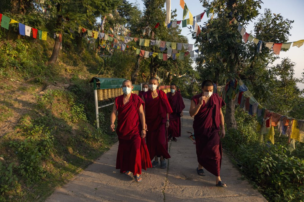 Exile Tibetan Buddhist monks wear masks as protection against the coronavirus as they circumambulate the residence of Tibetan spiritual leader the Dalai Lama in Dharmsala, India, Sunday, Sept