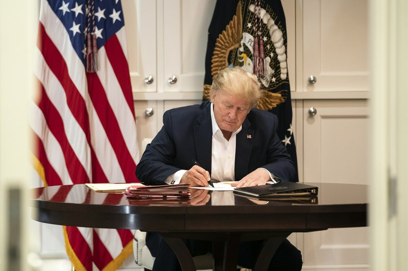 In this image released by the White House, President Donald Trump works in the Presidential Suite at Walter Reed National Military Medical Center in Bethesda, Md. Saturday, Oct. 3, 2020, afte