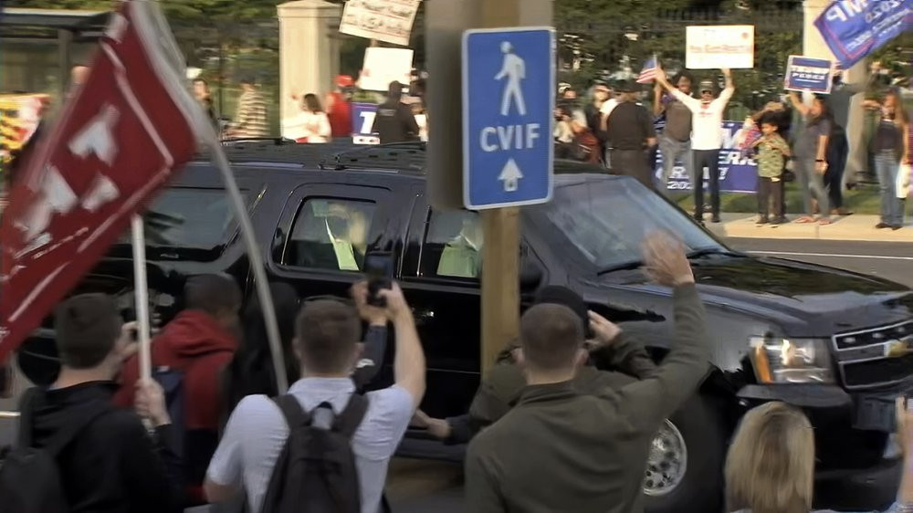 In this image from video, President Donald Trump waves as he drives past supporters gathered outside Walter Reed National Military Medical Center in Bethesda, Md., Sunday, Oct. 4, 2020.