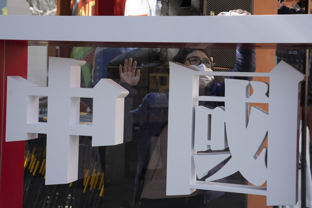 A worker cleans the panel with the words "China" written on it during a Chinese sporting goods brand promotion event in Beijing on Sunday, Oct. 4, 2020.