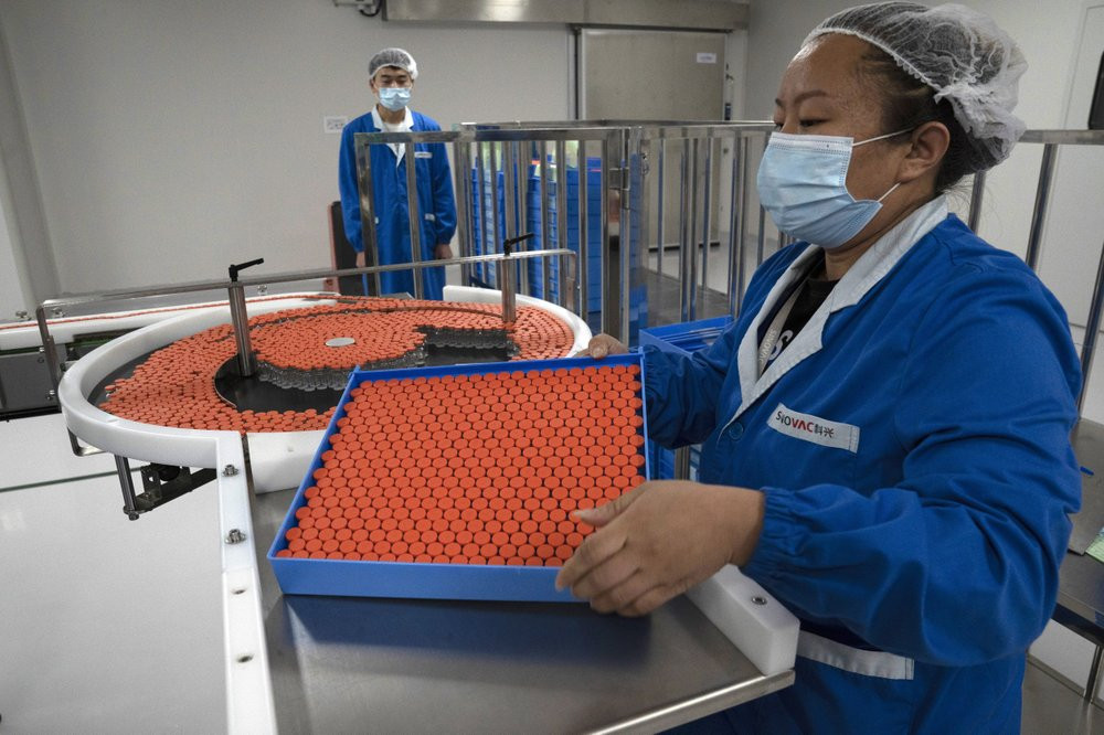 In this Sept. 24, 2020, file photo, a worker feeds vials for production of SARS CoV-2 Vaccine for COVID-19 at the SinoVac vaccine factory in Beijing.