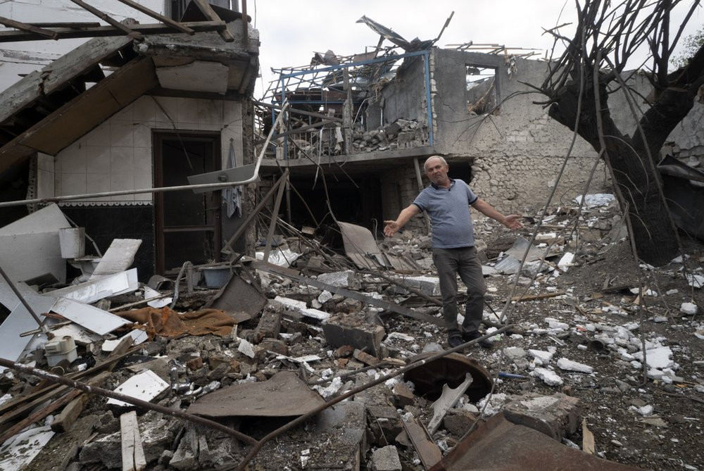 A man gestures in the yard of a house destroyed by shelling by Azerbaijan's artillery during a military conflict in Stepanakert, the separatist region of Nagorno-Karabakh, Friday, Oct. 9, 202