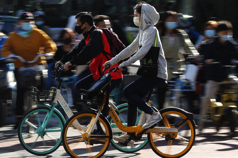 People wearing face masks to help curb the spread of the coronavirus ride bicycle during the morning rush hour in Beijing, Monday, Oct. 12, 2020.