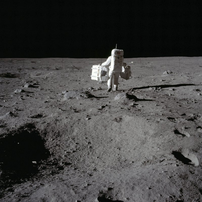 In this July 20, 1969 photo made available by NASA, lunar module pilot Buzz Aldrin carries a seismic experiments package in his left hand and the Laser Ranging Retroreflector to the deploymen