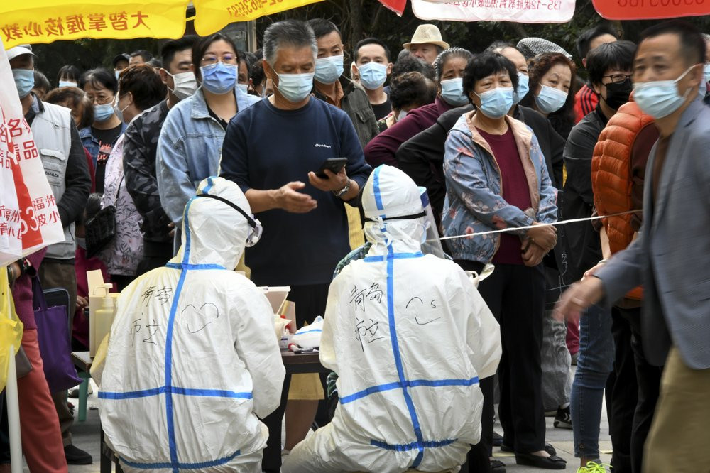 In this photo released by Xinhua News Agency, residents wearing face masks to help curb the spread of the coronavirus line up for the COVID-19 test near the residential area in Qingdao in eas