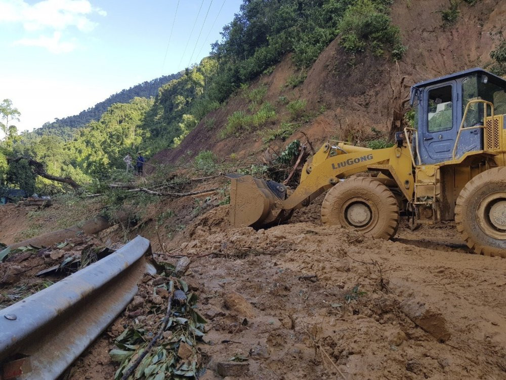 A bulldozer clears out the road damaged by landslide to access a village swamped by another landslide in Quang Nam province, Vietnam on Thursday, Oct. 29, 2020.