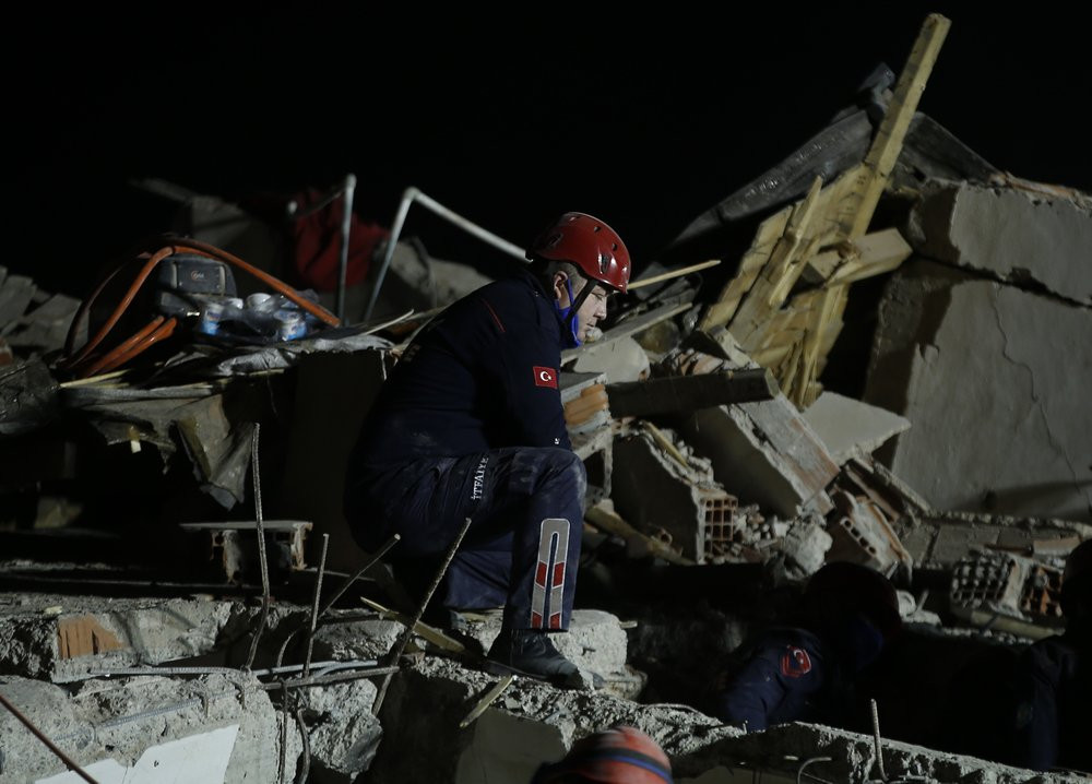A member of rescue services, kneels to listen during the ongoing search for survivors in the debris of a collapsed building in Izmir, Turkey, Saturday, Oct. 31, 2020.