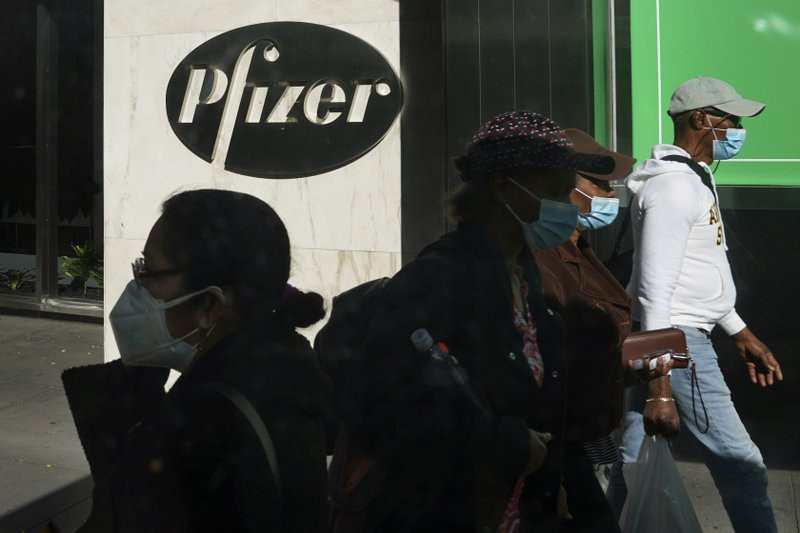 Pedestrians walk past Pfizer world headquarters in New York on Monday Nov. 9, 2020. Pfizer says an early peek at its vaccine data suggests the shots may be 90% effective at preventing COVID-1