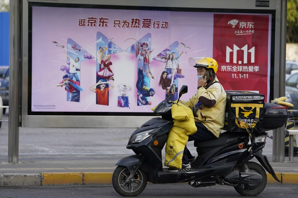 A delivery man passes by an ad for the Nov. 11 Sales Day in Beijing, China on Oct. 28, 2020.