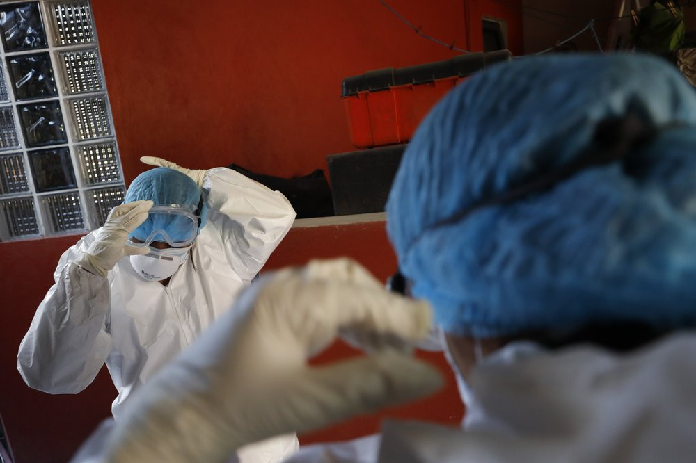 Doctors Delia Caudillo, left, and Monserrat Castaneda, put on protective gear as they prepare to conduct a COVID-19 test at a home in the Venustiano Carranza borough of Mexico City, Thursday,