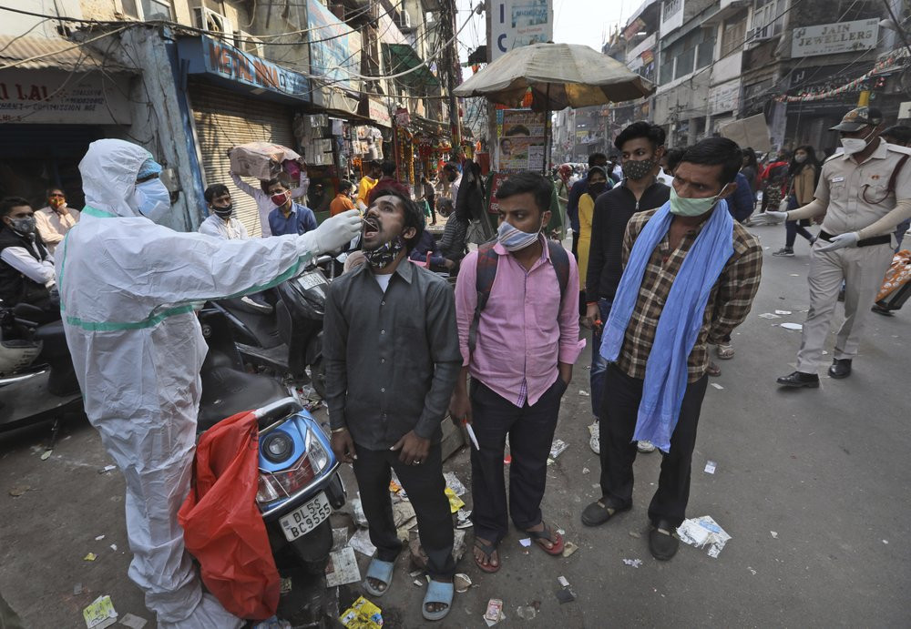 A health worker takes a sample to test for COVID-19 test at a market place in New Delhi, India, Thursday, Nov. 19, 2020.