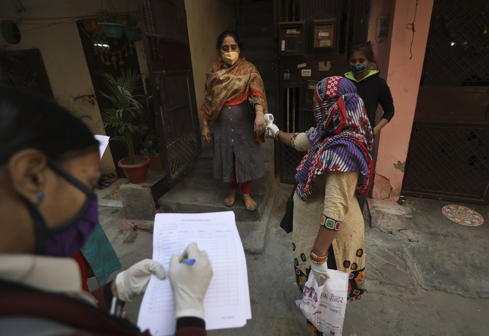 A health worker reads the temperature of a woman during a door to door survey to assess the COVID-19 situation in New Delhi, India, Monday, Nov. 23, 2020.