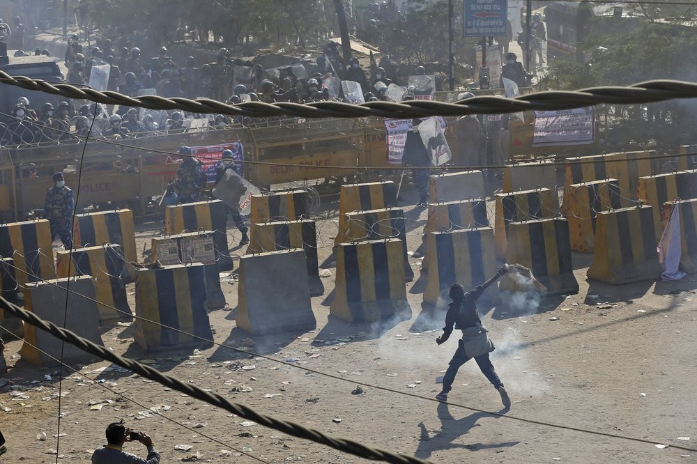 A farmer throws back a tear gas shells towards policemen, at the border between Delhi and Haryana state, Friday, Nov. 27, 2020.