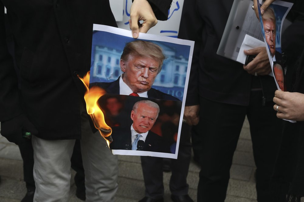 A group of protesters burn pictures of the U.S. President Donald Trump, top, and the President-elect Joe Biden in a gathering in front of Iranian Foreign Ministry on Saturday, Nov. 28, 2020, 