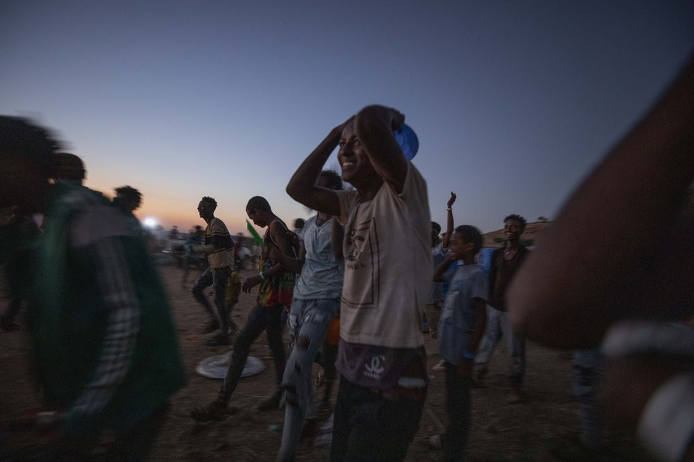 Tigray men who fled the conflict in Ethiopia's Tigray region, run to recieve cooked rice from charity organization Muslim Aid, at Umm Rakouba refugee camp in Qadarif, eastern Sudan, Friday, N