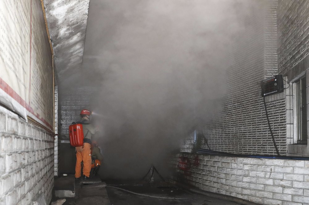In this photo released by Xinhua News Agency, rescue workers gauge the density of carbon monoxide in the smog at the entrance of the coal mine in Yongchuan District of Chongqing, southwestern