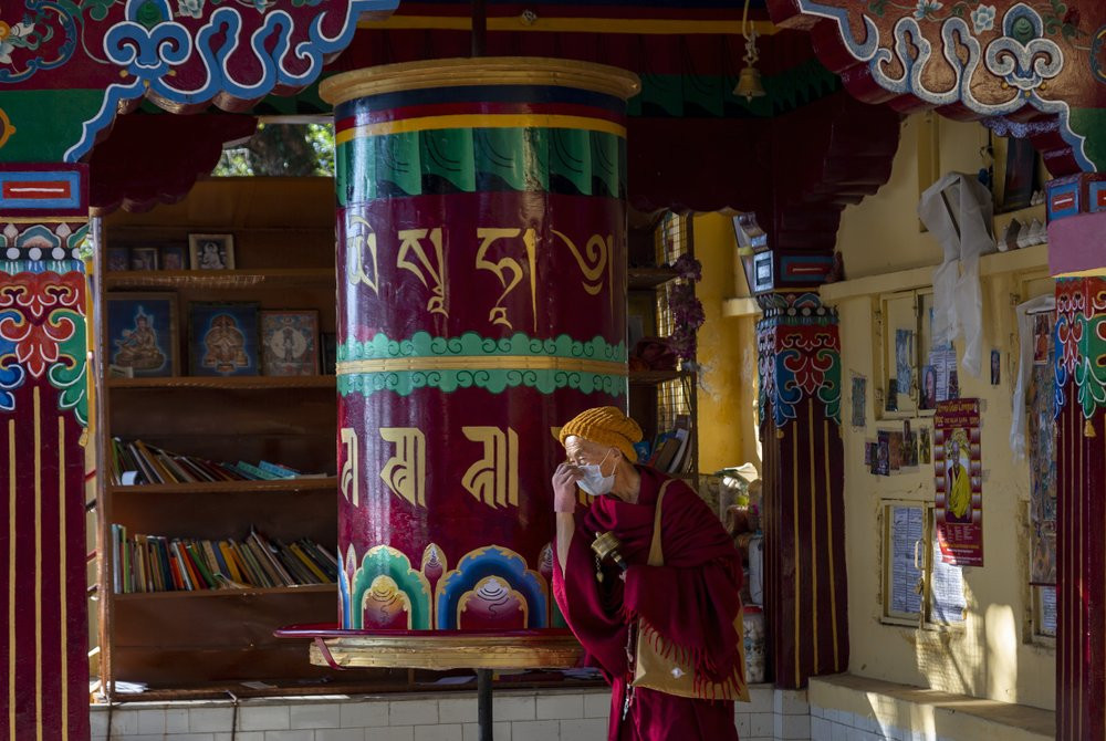 An exile Tibetan Buddhist monk wearing a mask as precaution against the coronavirus rotates a prayer wheel in Dharmsala, India, Friday, Dec. 18, 2020.