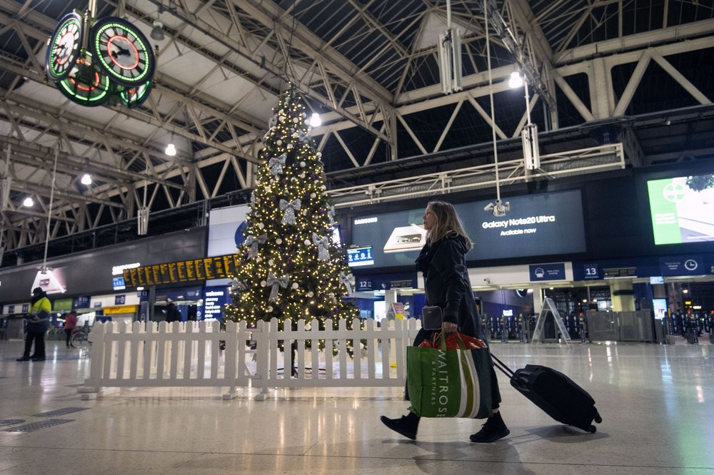 A woman pulls a suitcase past the Christmas tree on the concourse of Waterloo Station in central London, Sunday, Dec. 20, 2020.
