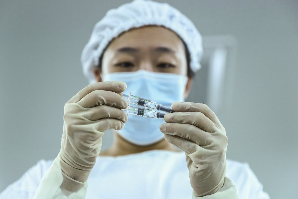 In this Dec. 25, 2020 file photo, a staff member inspects syringes of COVID-19 inactivated vaccine products at a packaging plant of the Beijing Biological Products Institute Co., Ltd, a unit 