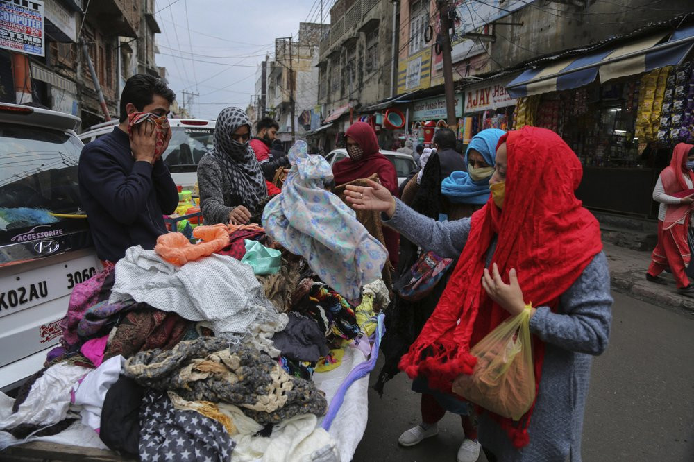 Indians, some of them, wearing face masks as a precautionary measure against the coronavirus shop at a Sunday market in Jammu, India, Sunday, Jan.3, 2021.