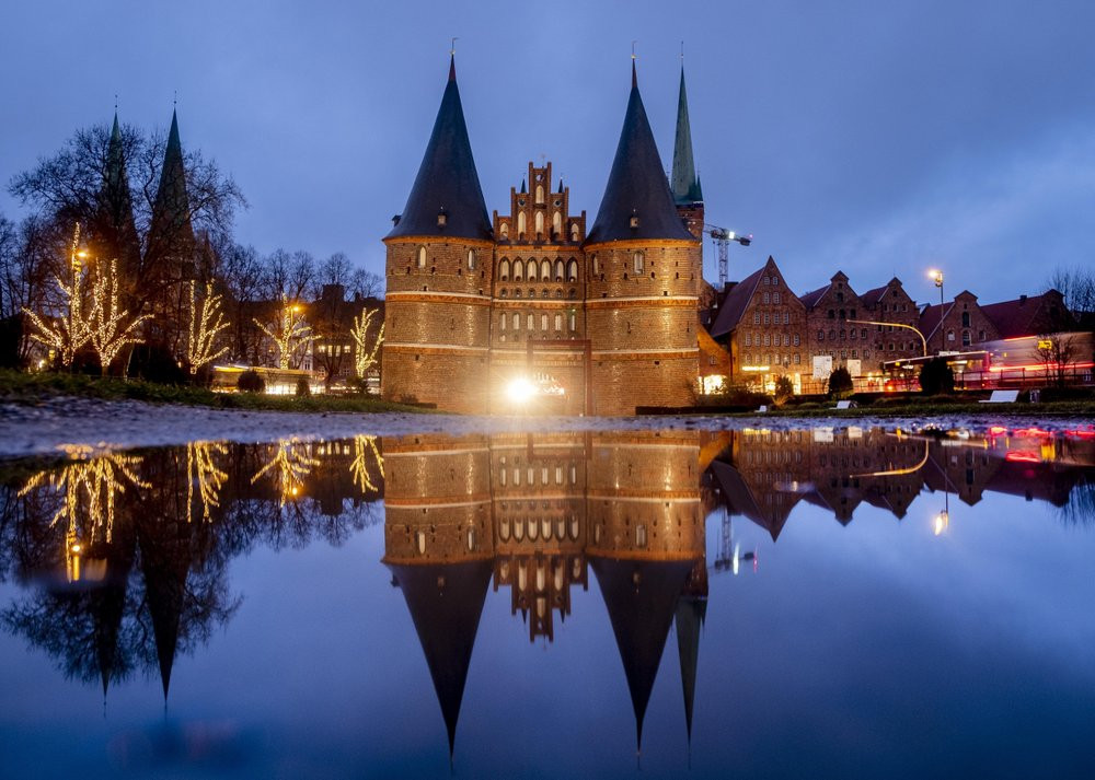 The medieval Holstentor is reflected in water in Luebeck, Germany, Monday, Jan. 4, 2021. The German government will decide about further restrictions to avoid the outspread of coronavirus on 