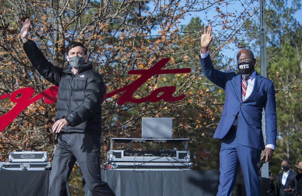 Jon Ossoff, left, and Raphael Warnock wave to the crowd during a campaign rally in Augusta, Georgia, Monday, Jan. 4, 2021.